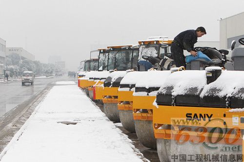 寒風(fēng)中，工人細(xì)心地除去壓路機(jī)上的積雪